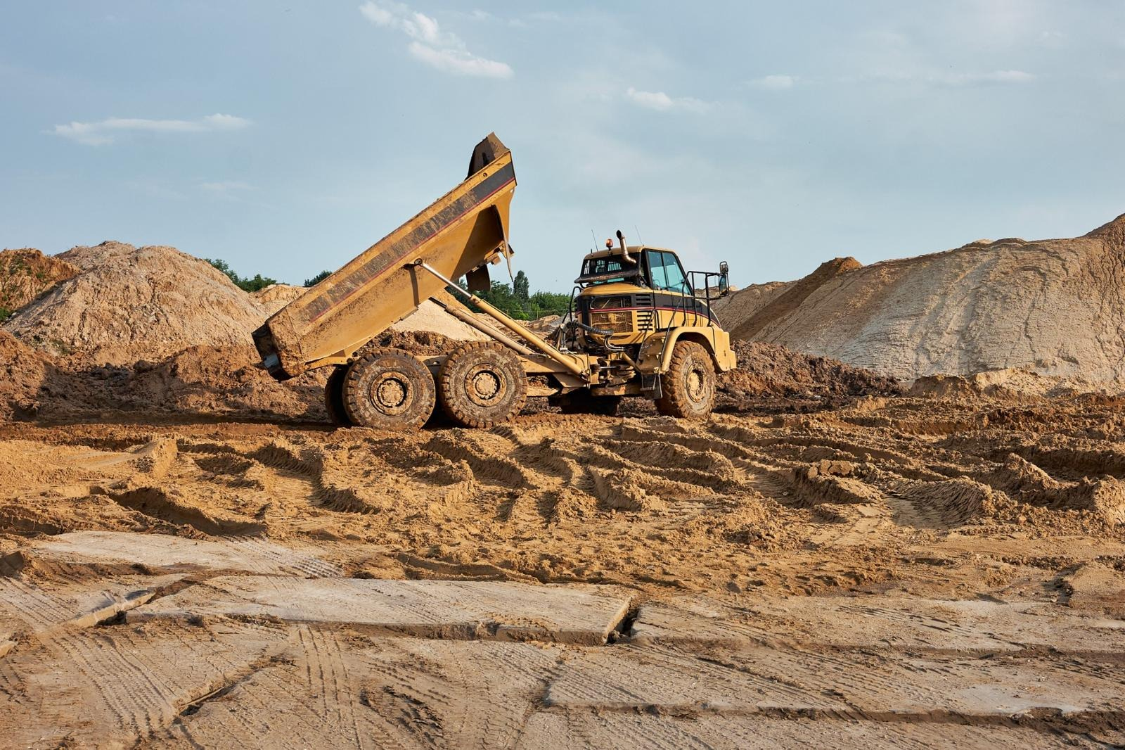 Ciężarówka wyładowująca piasek na placu budowy w Lubinie – transport kruszyw i materiałów sypkich.